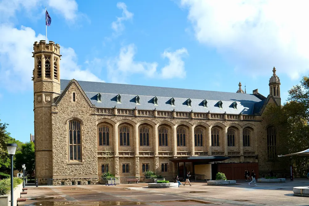 Bonython Hall, the iconic gothic sandstone great hall of the University of Adelaide on North Terrace, Adelaide, Australia, under a bright blue daytime sky.