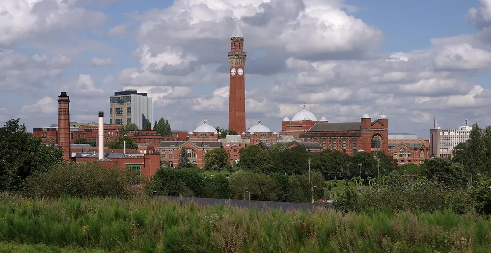 Panoramic daytime view of the University of Birmingham Edgbaston campus, with the Joseph Chamberlain Memorial Clock Tower ("Old Joe") and the domed Aston Webb Building under a blue sky