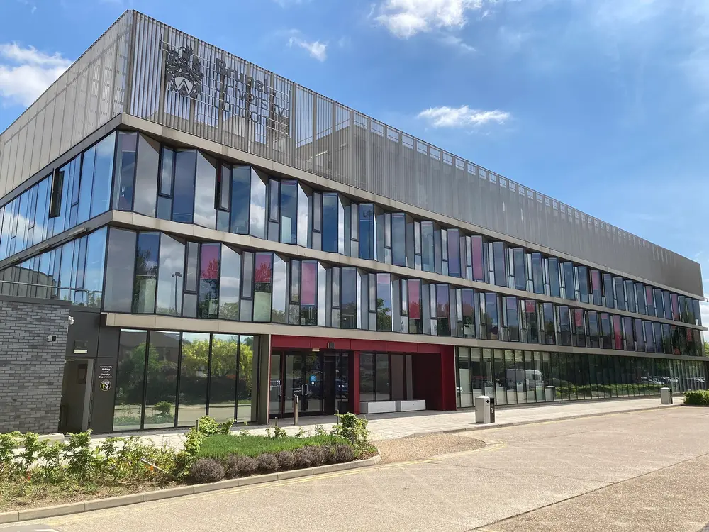 The STEM Centre at Brunel University London, Uxbridge — a modern glass-fronted building bearing the university's name and crest, under a clear blue sky.