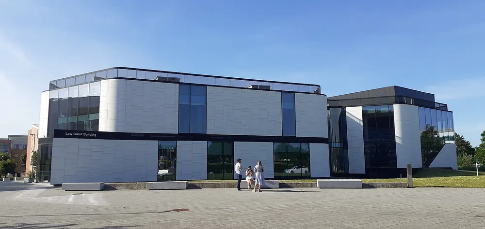 The Law Court Building, University of Hertfordshire (College Lane Campus, Hatfield) — modern white-and-glass exterior under a clear blue sky.