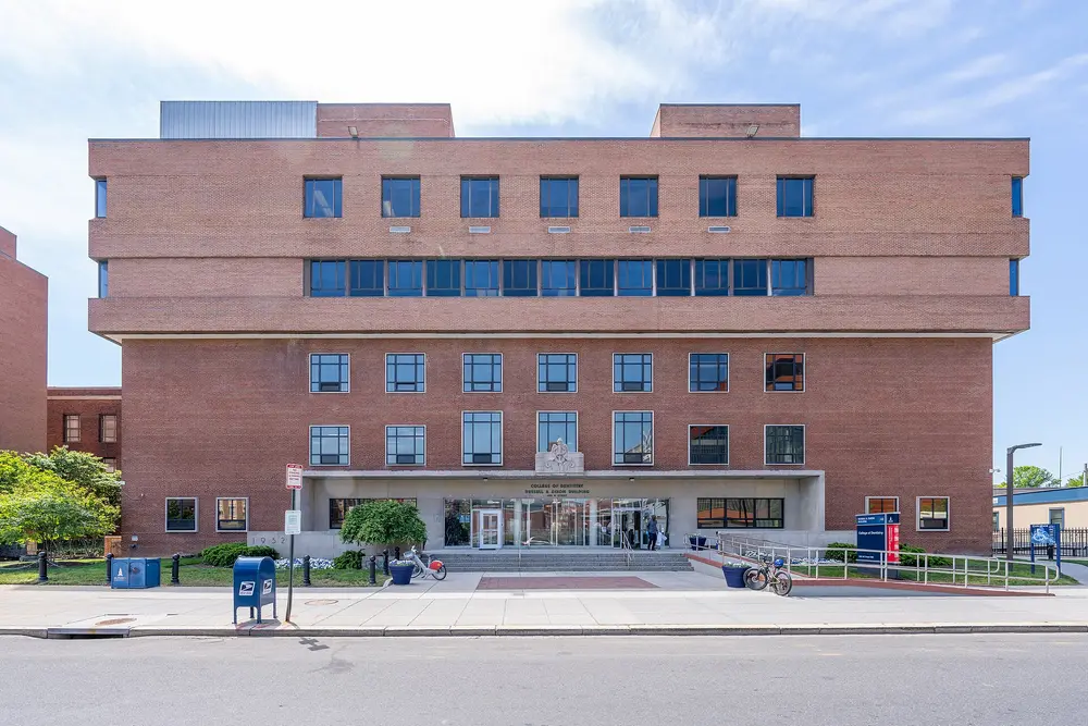 Exterior of Howard University College of Dentistry (Russell A. Dixon Building), Washington, DC — daytime frontal view of the red-brick facade under a blue sky.