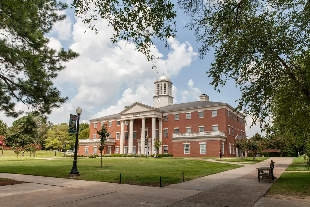 The iconic main academic building of Lyon College (red brick with white columns and a cupola clock tower), the host institution of the Lyon College School of Dental Medicine, on its Batesville, Arkansas campus.