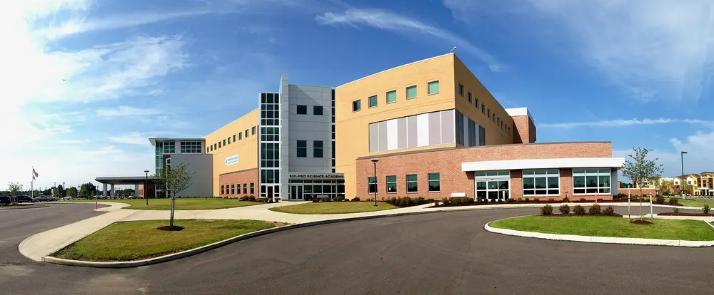 Modern NEOMED Education and Wellness Center (NEW Center) building on the Northeast Ohio Medical University campus in Rootstown, Ohio, under a blue sky with green lawn.