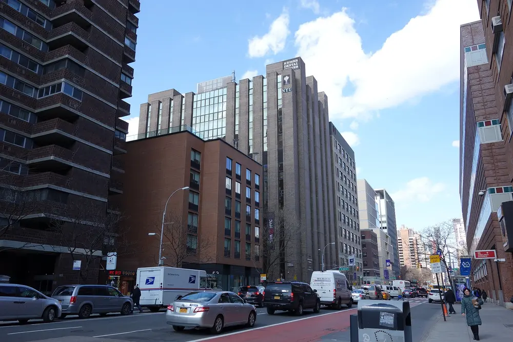 Daytime street view of the NYU College of Dentistry's Kriser Dental Center building on First Avenue at E 24th St, Manhattan, New York, with blue sky.