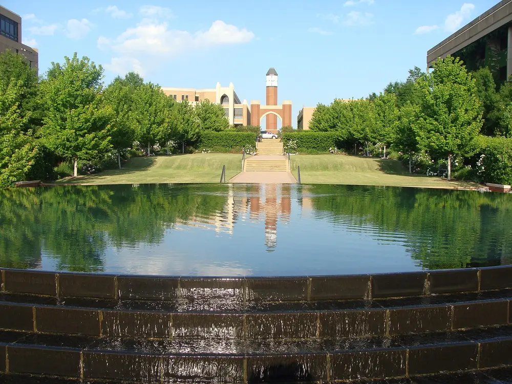 University of Oklahoma Health Sciences Center campus in Oklahoma City — a reflecting pool/fountain, rose gardens and tree-lined lawn leading to a brick clock-tower building; this is the academic medical center campus that houses the OU College of Dentistry.