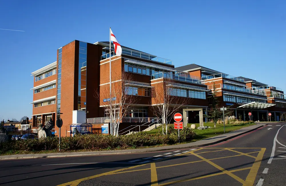 St George's Hospital / St George's, University of London campus (Atkinson Morley Wing), Tooting, London, under a clear blue sky with the St George's flag flying