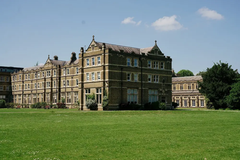 The historic main college building of St Mary's University, Twickenham, viewed across the front lawn under a blue sky