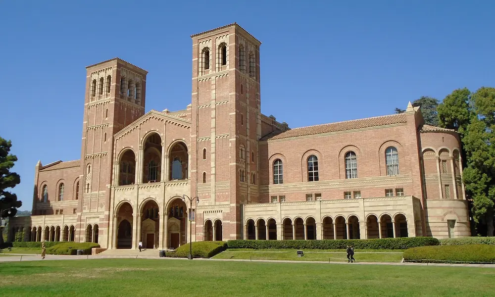 Royce Hall, the iconic Romanesque Revival landmark on the UCLA Westwood campus in Los Angeles (host university of the UCLA School of Dentistry), daytime exterior with clear blue sky and green lawn.
