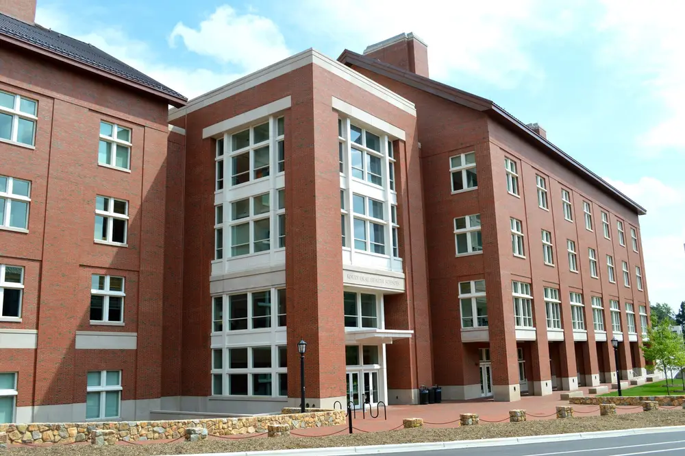 Exterior of the Koury Oral Health Sciences Building at UNC-Chapel Hill, home of the UNC Adams School of Dentistry, red-brick facade under blue sky.