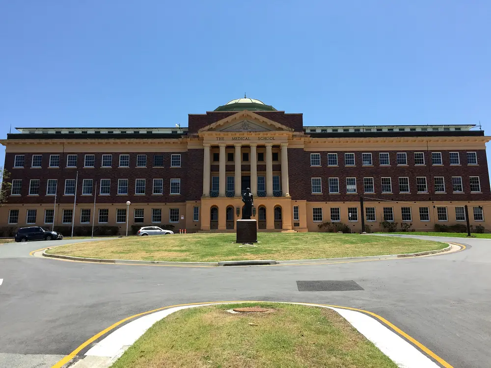 Front facade of the University of Queensland Mayne Medical School building (historic brick-and-sandstone hall with green dome and columned portico reading "THE MEDICAL SCHOOL") at Herston, Brisbane, Australia.