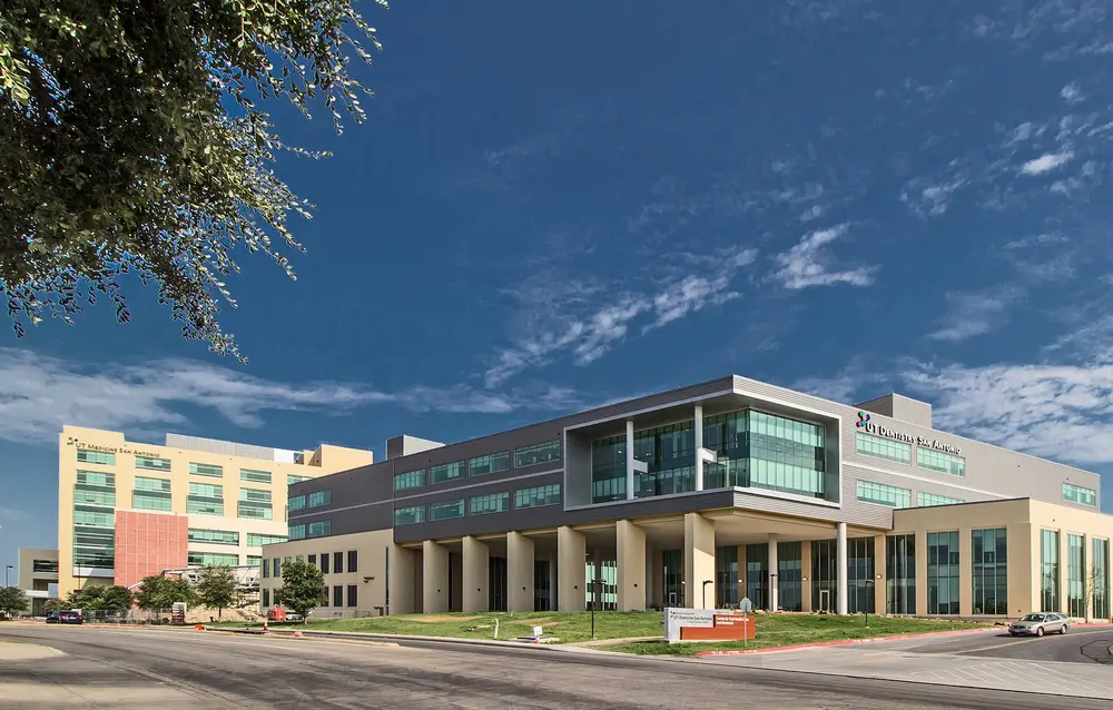 Exterior of the UT Dentistry San Antonio building (Center for Oral Health Care & Research), the home of UT Health San Antonio School of Dentistry, under a clear blue sky.