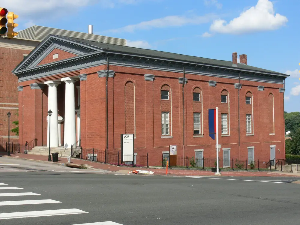 Exterior of a red-brick classical building with white columns on the VCU Medical Center / MCV (Medical College of Virginia) Campus in Richmond, VA — the health-sciences campus that houses the VCU School of Dentistry.